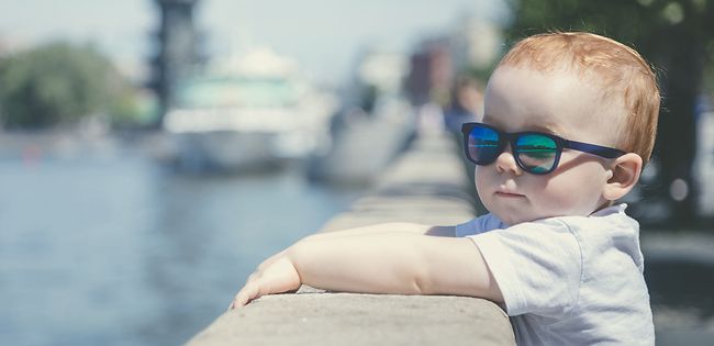 Child in sunglasses looking at river